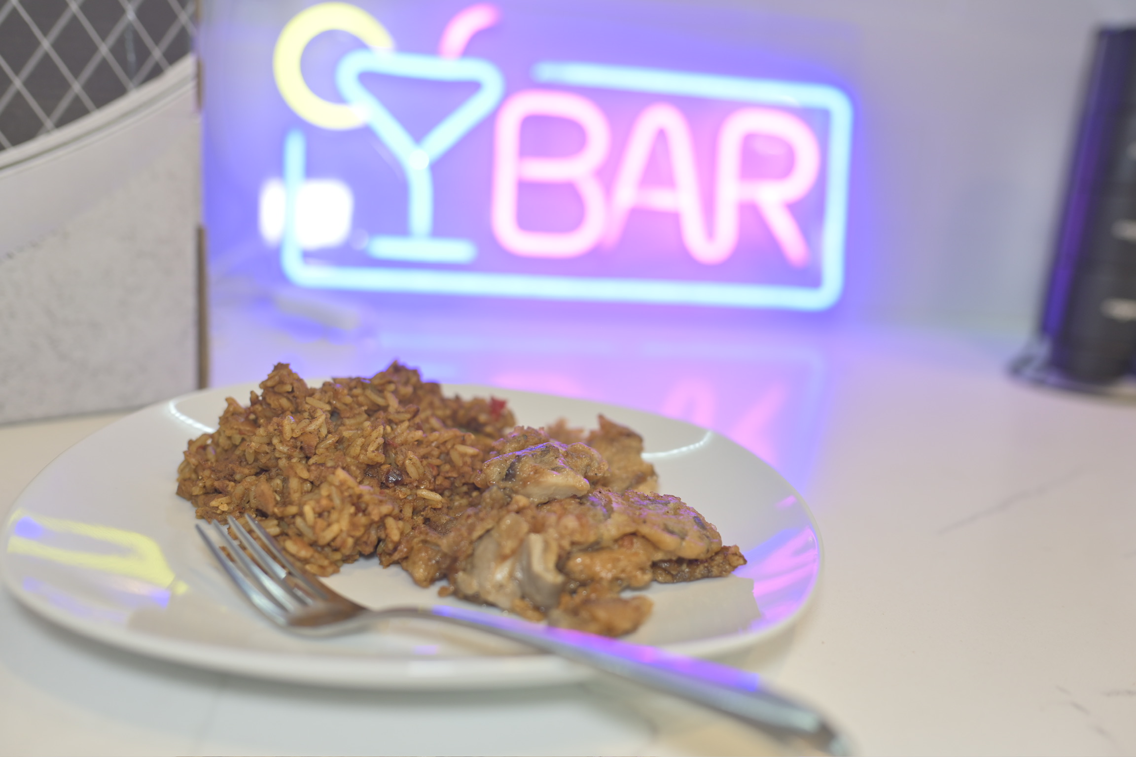 A plated meal set in front of a neon bar sign